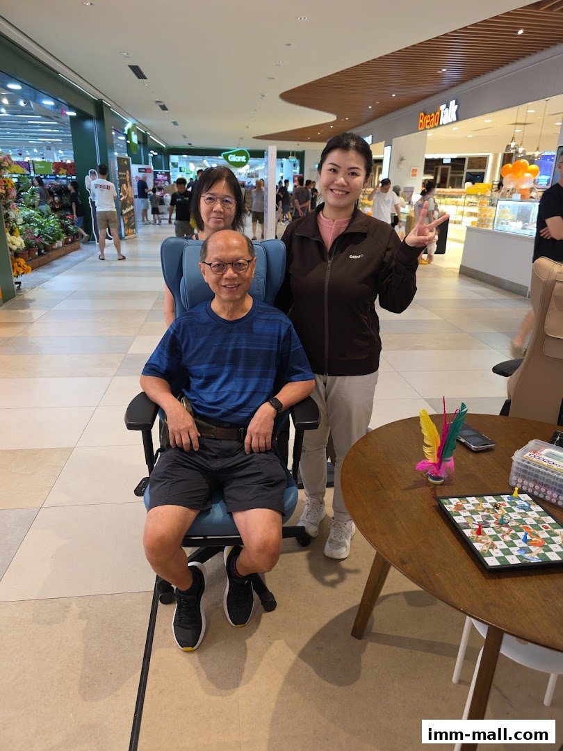 A family poses for a photo in a shopping mall, with a massage chair and a game on a table.