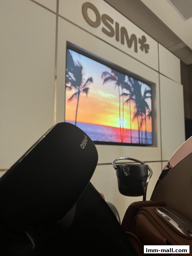 A close-up view of an OSIM massage chair with a screen displaying a tropical sunset.