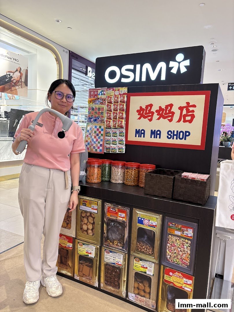 A woman holds a massage device in front of an OSIM store display featuring snacks and a 'Ma Ma Shop' sign.