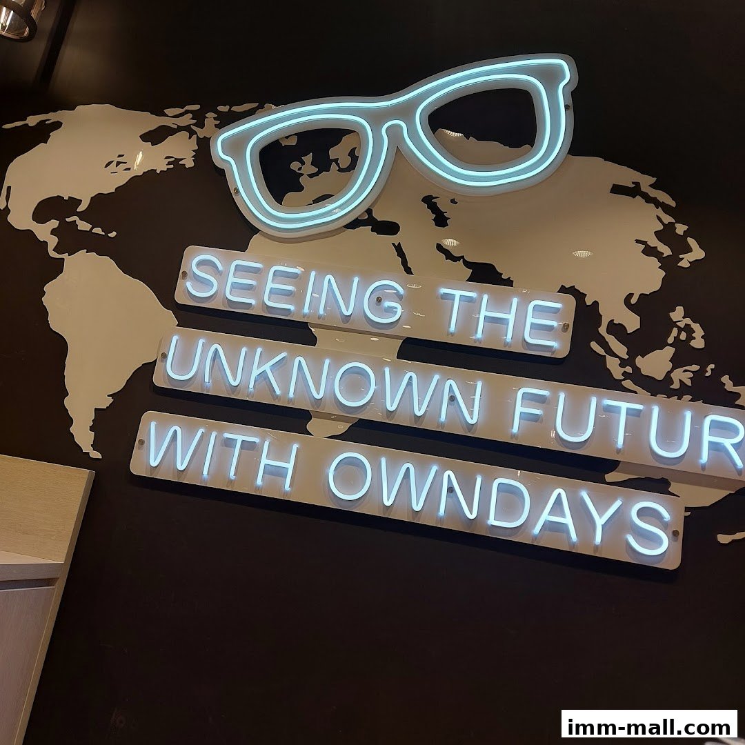 Neon sign with glasses and text 'Seeing the Unknown Future with OWNDAYS' on a world map.