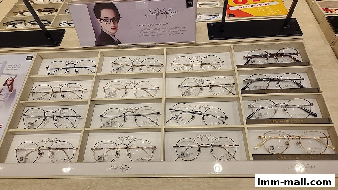 A display of various eyeglasses, featuring the John Dillinger brand, in a retail setting.