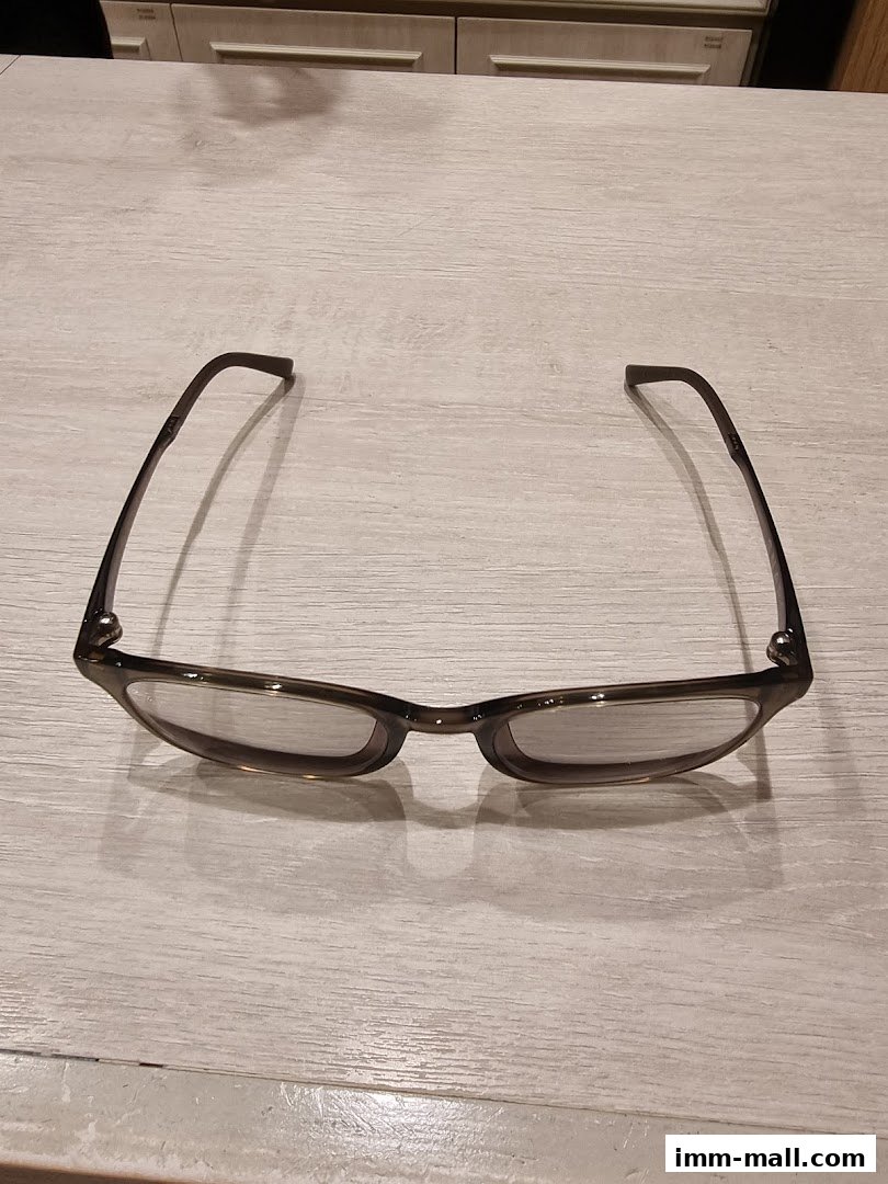 A pair of stylish, dark-rimmed eyeglasses with clear lenses resting on a light wooden surface.