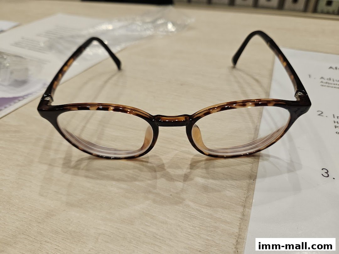 A pair of tortoiseshell eyeglasses with clear lenses rests on a wooden surface.