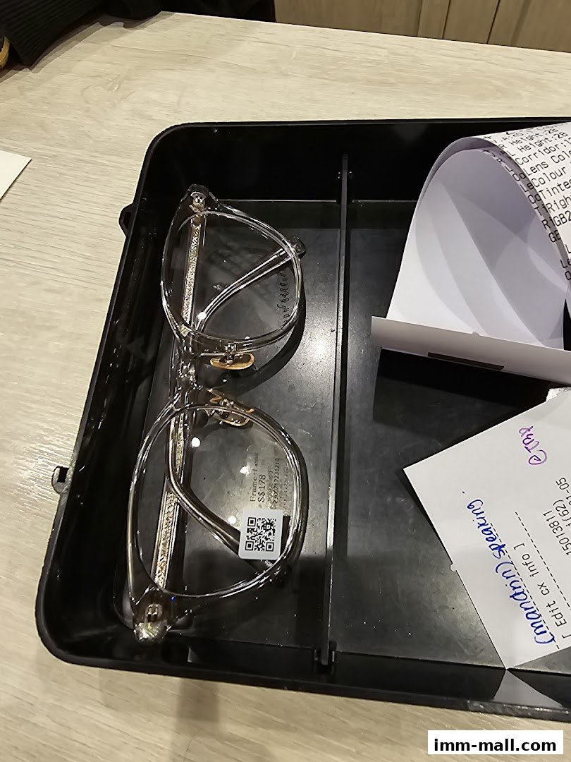 A pair of clear-framed glasses sits in a black tray next to a receipt.