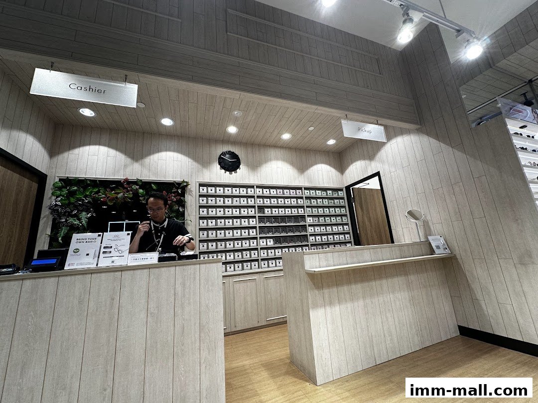 A man stands behind a counter in a modern eyewear shop with shelves of glasses.