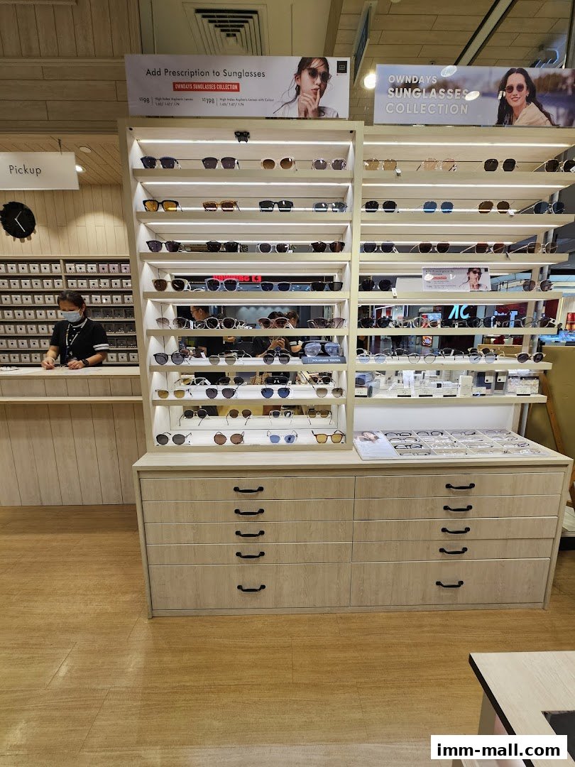 A display of sunglasses and eyeglasses at OWNDAYS IMM outlet with a staff member at the counter.