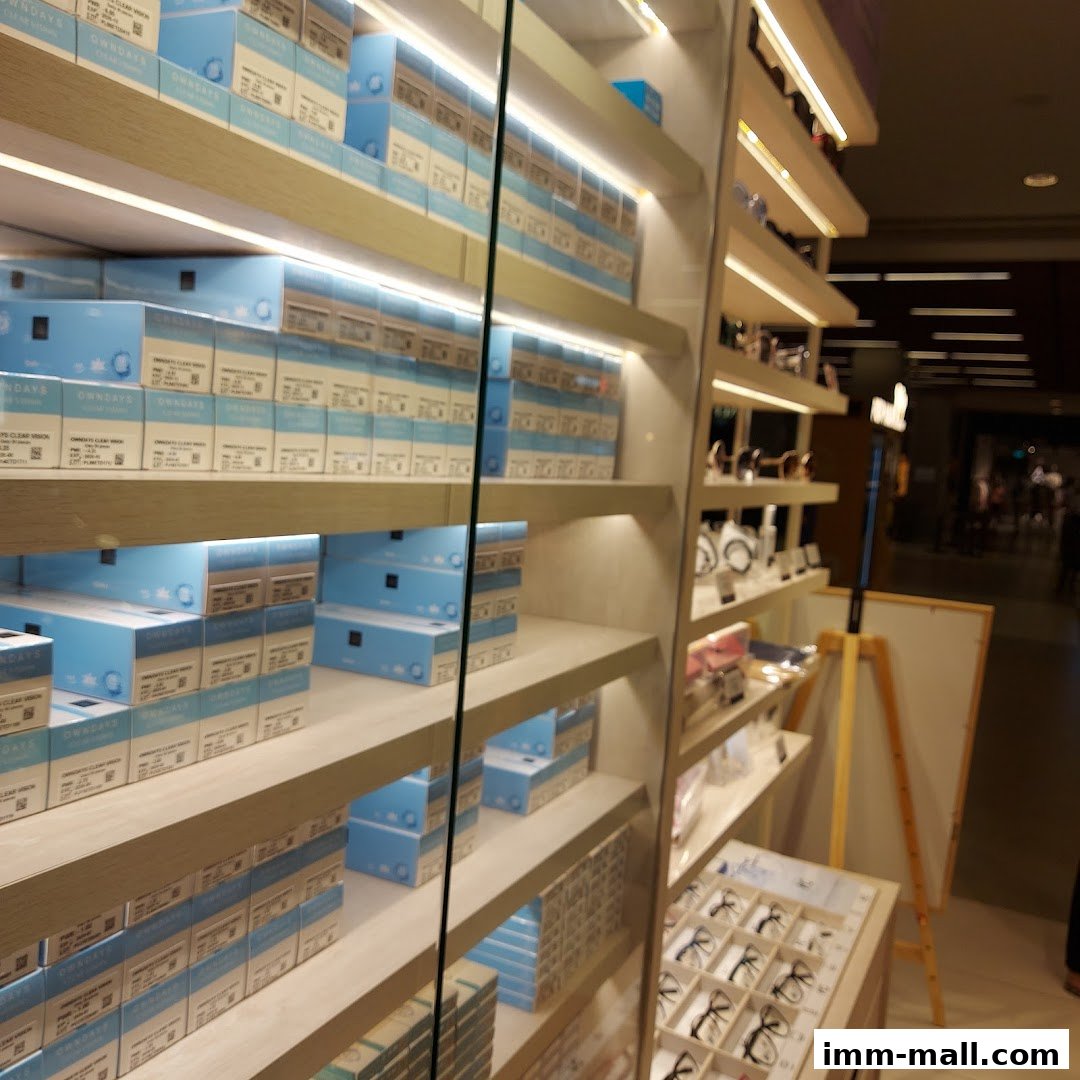 Shelves stocked with boxes of contact lenses and displays of eyeglasses in a retail store.