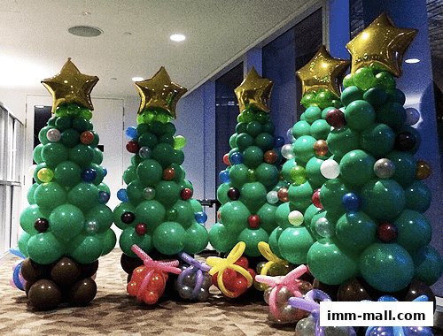 Several festive balloon Christmas trees decorated with stars and ornaments, with balloon gifts at their bases.