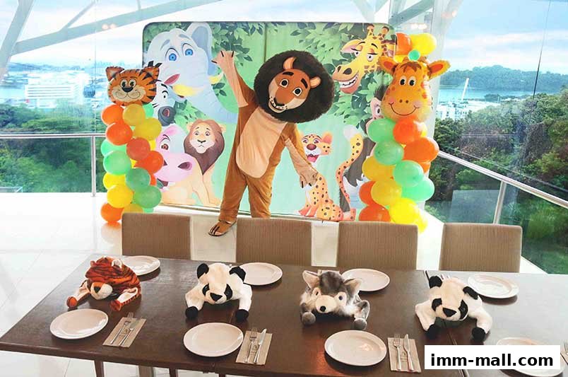 A table set for a jungle-themed party with animal plushies and balloons.