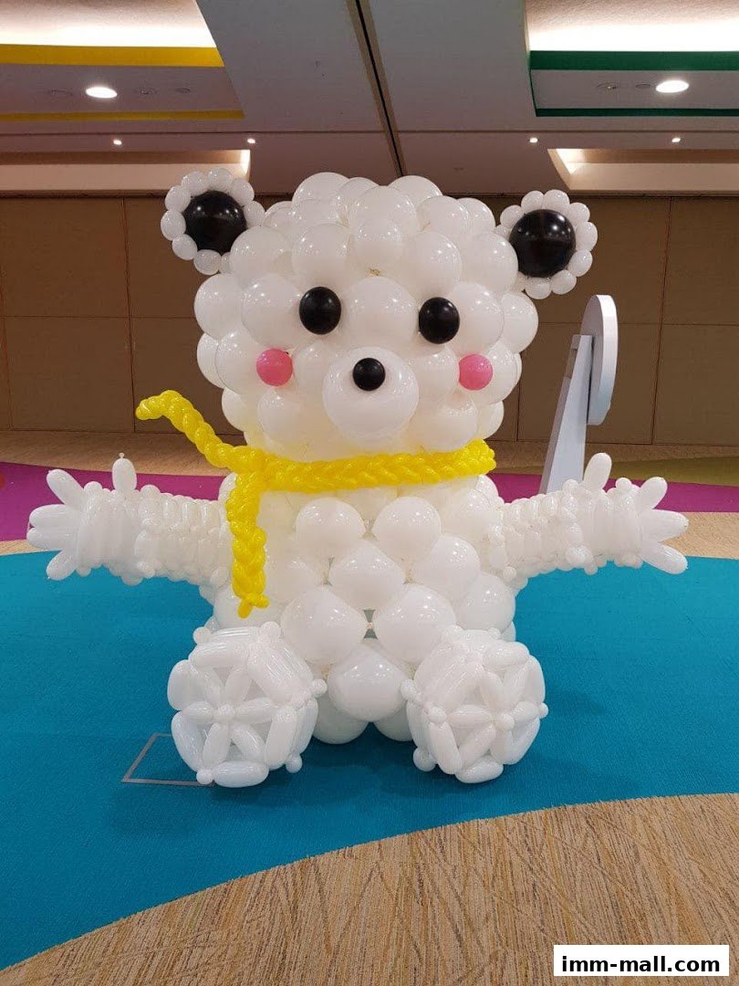 A large balloon sculpture of a white bear wearing a yellow scarf.