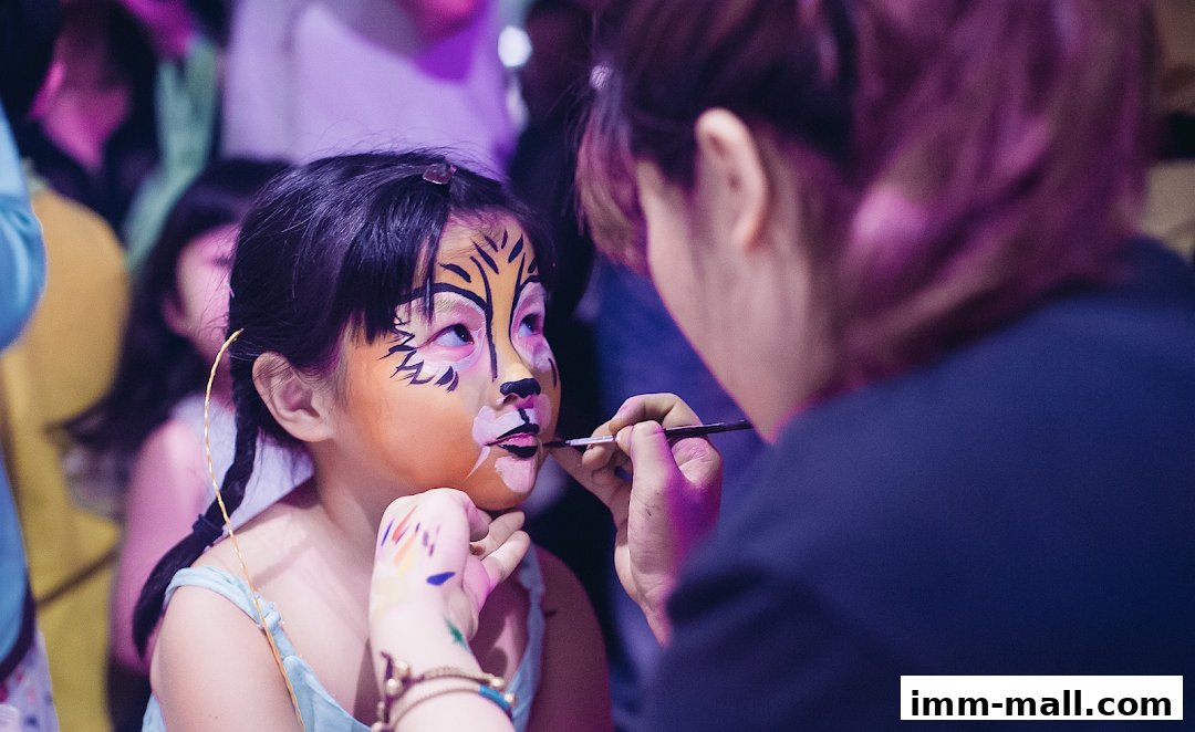 A child is getting their face painted with a tiger design by an artist.