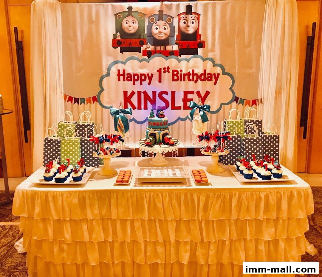A dessert table set up for a child's first birthday party with a Thomas the Tank Engine theme.