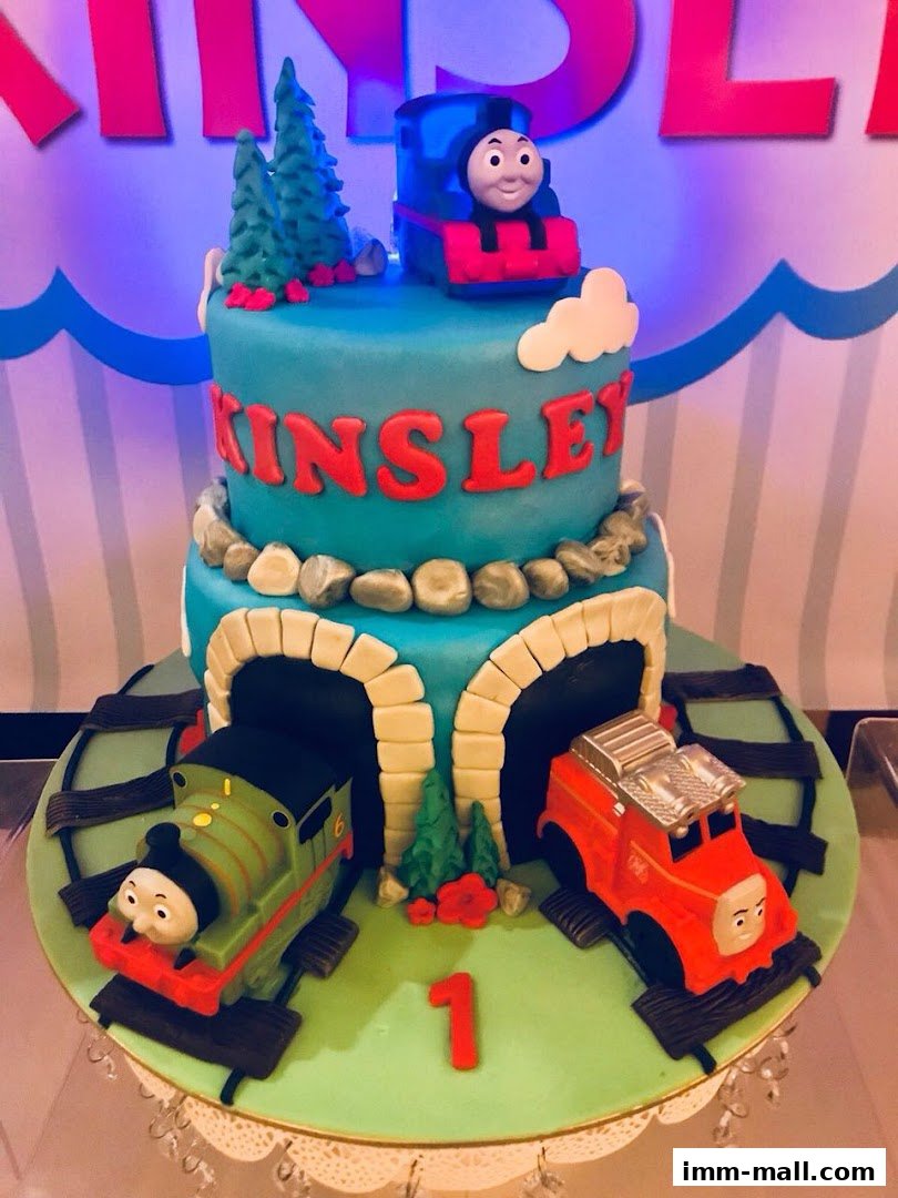 A two-tiered Thomas the Tank Engine themed birthday cake with edible trains and tunnels.