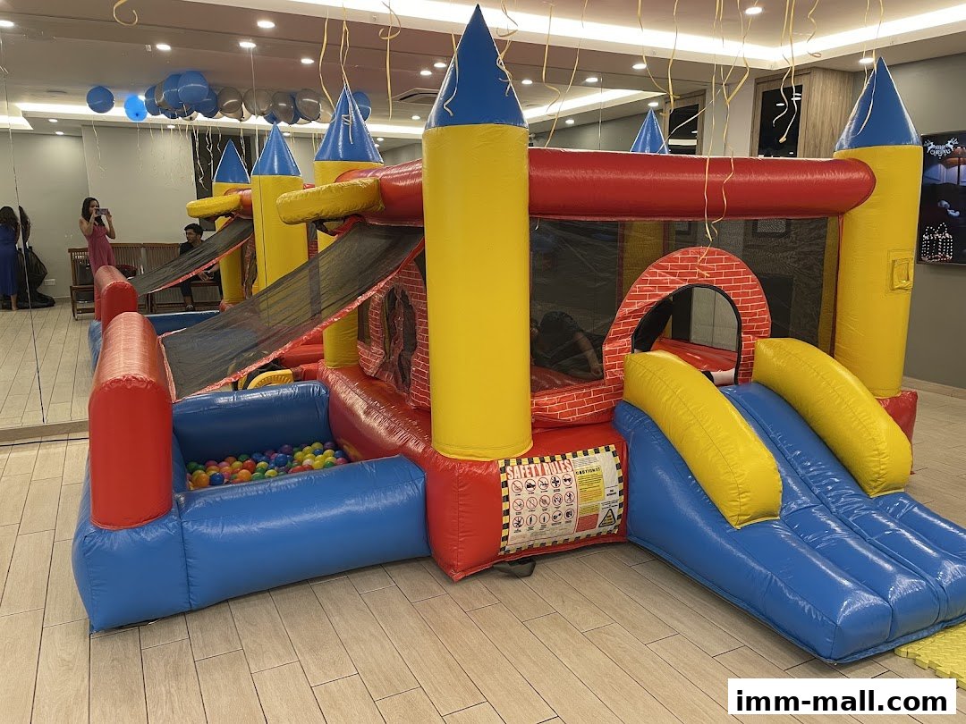 A colorful inflatable castle with slides and a ball pit, set up indoors.
