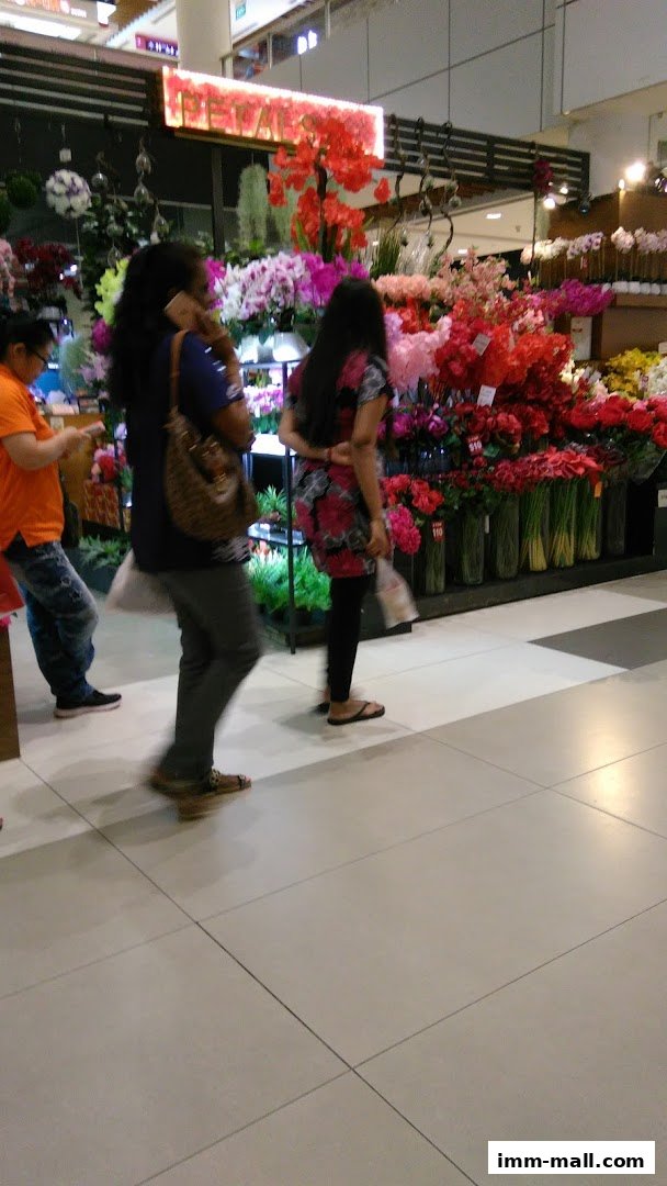 People browsing a vibrant flower shop with a wide selection of colorful artificial flowers.