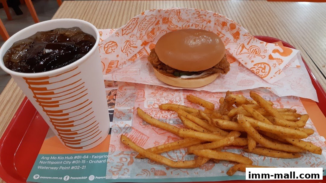 A Popeyes chicken sandwich meal with fries and a drink on a red tray.