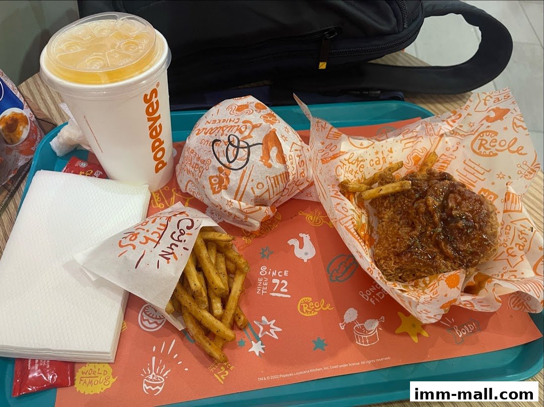 A tray of Popeyes Louisiana Kitchen food including a burger, fried chicken, Cajun fries, and a drink.