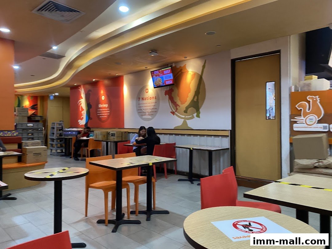 Interior view of a Popeyes restaurant with tables, chairs, and wall decor.