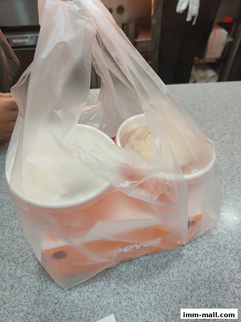 A plastic bag filled with Popeyes food containers and cups on a counter.