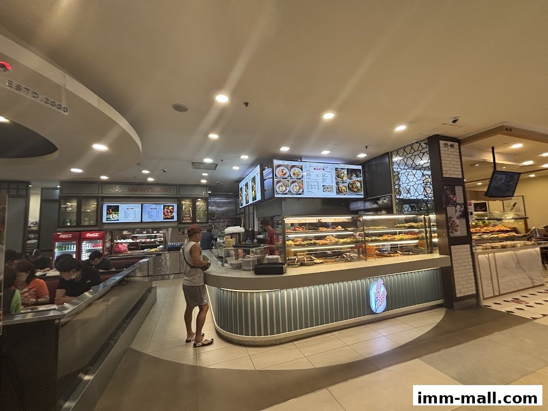 A busy food stall with a display of food and customers ordering.