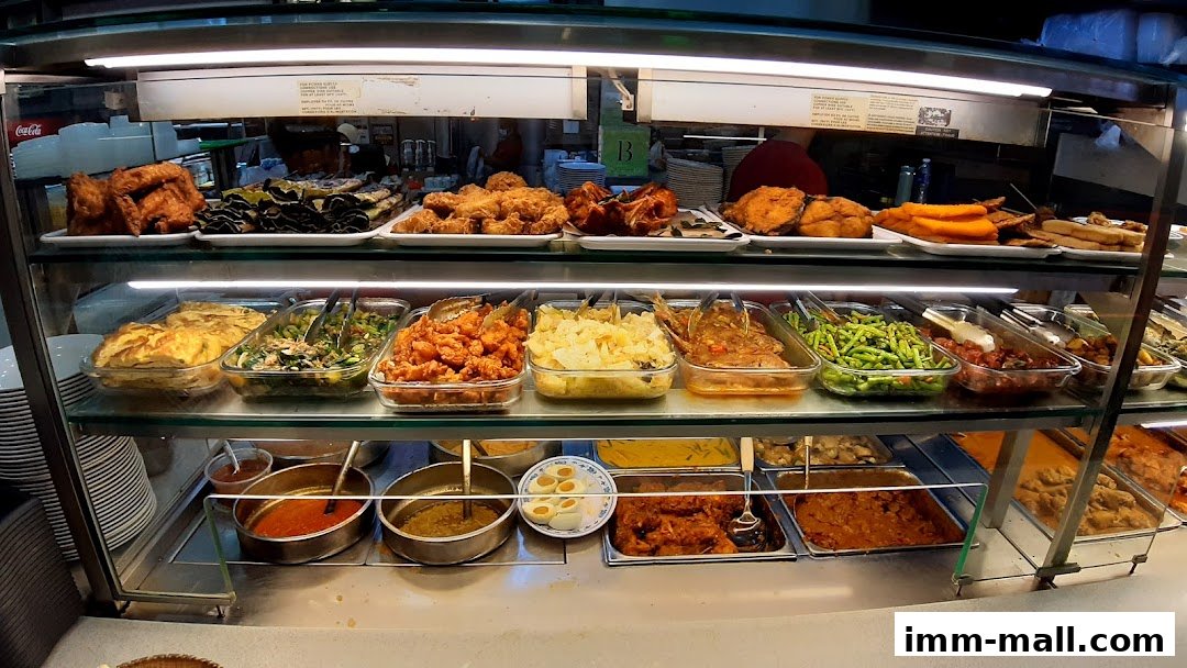 A display case filled with various cooked dishes, including fried chicken, vegetables, and curries.