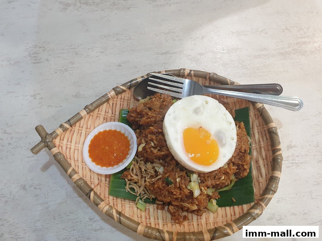 A plate of fried rice topped with a sunny-side-up egg and a side of chili sauce.