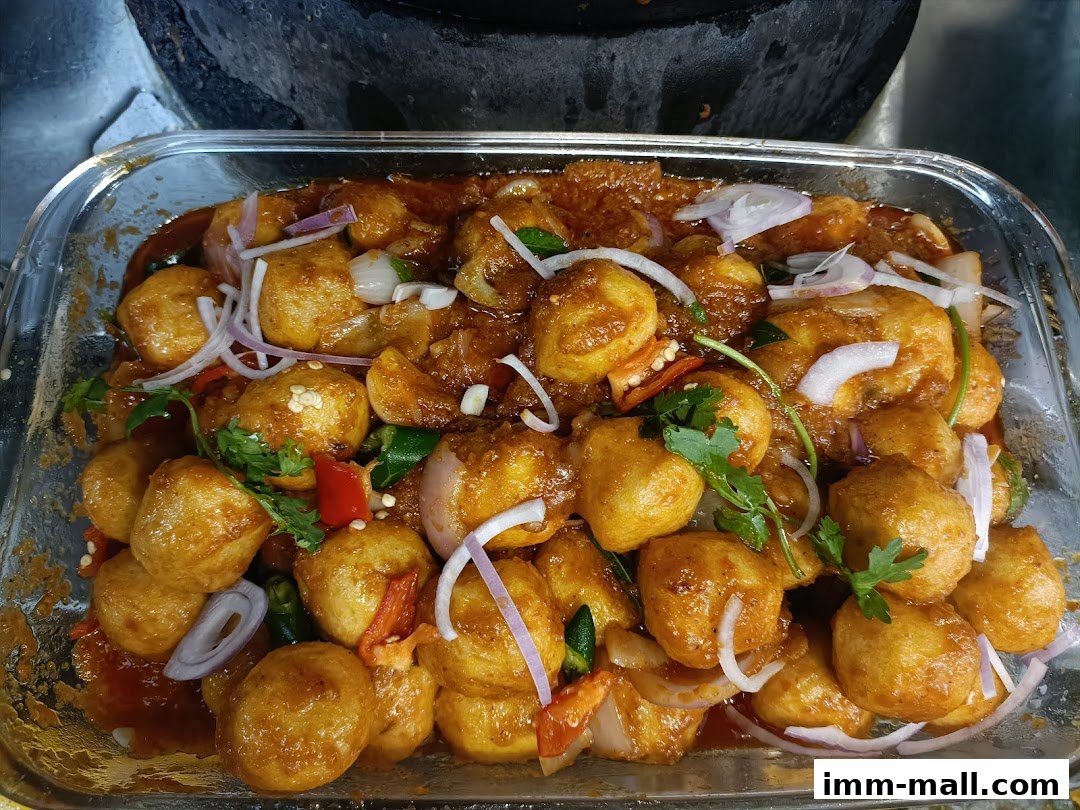A close-up of a dish with round, golden-brown pieces in a savory sauce with onions and cilantro.