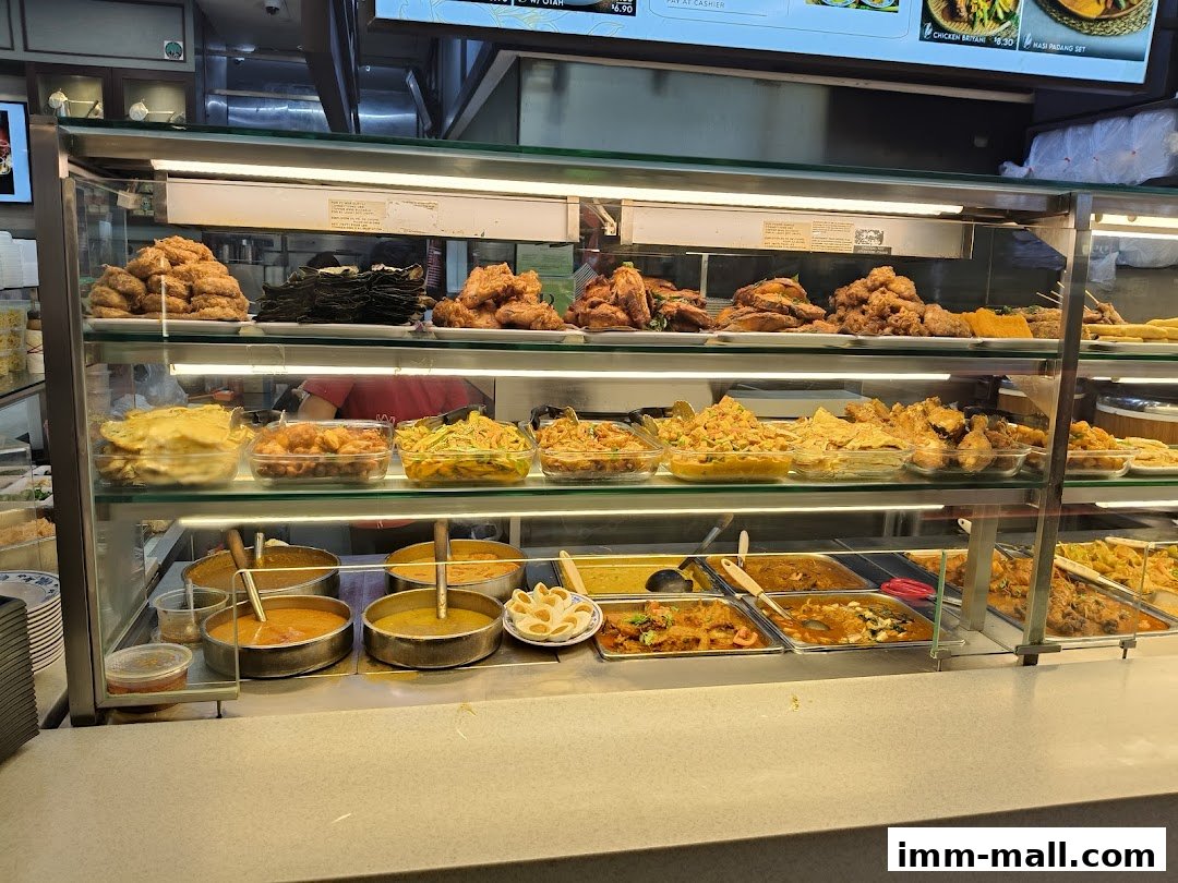 A display case filled with various dishes, including fried items, curries, and side dishes.