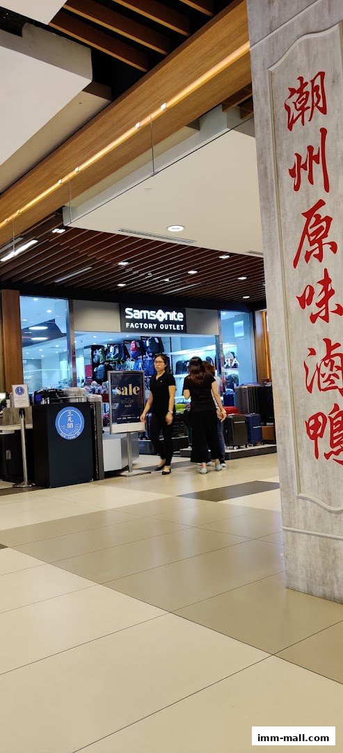 The entrance to Samsonite Factory Outlet with a sale sign and people walking by.