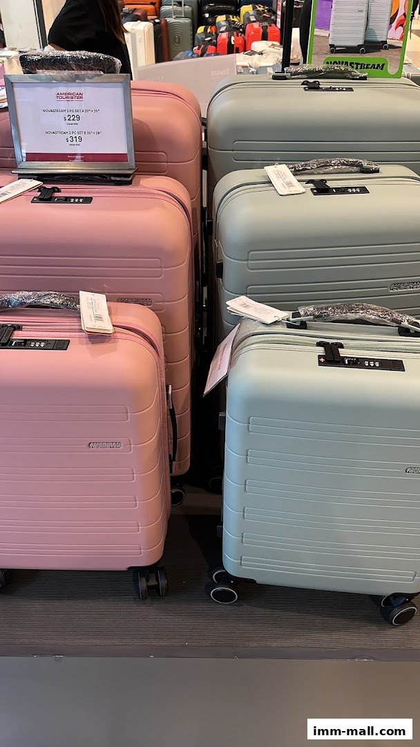 A display of pink and light green American Tourister suitcases in various sizes.