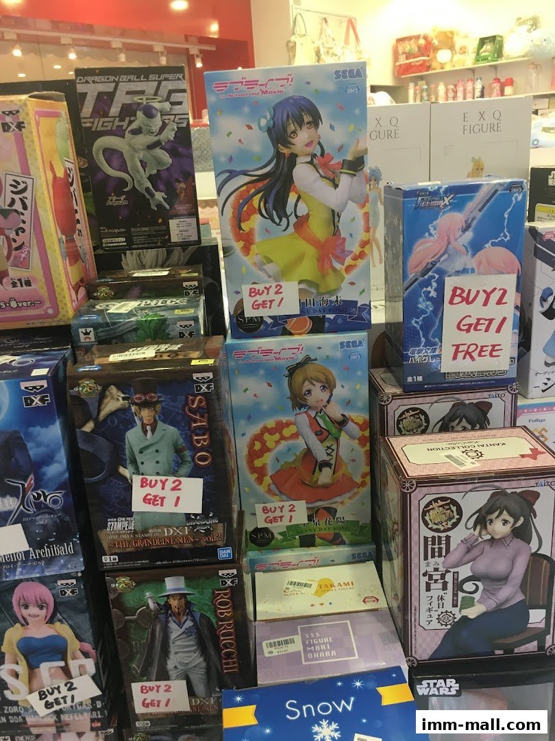 A display of anime and manga collectible figures, many with 'Buy 2 Get 1 Free' signs.