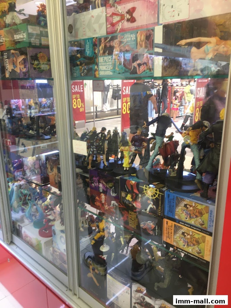 A display window filled with anime figurines and merchandise, with sale signs visible.