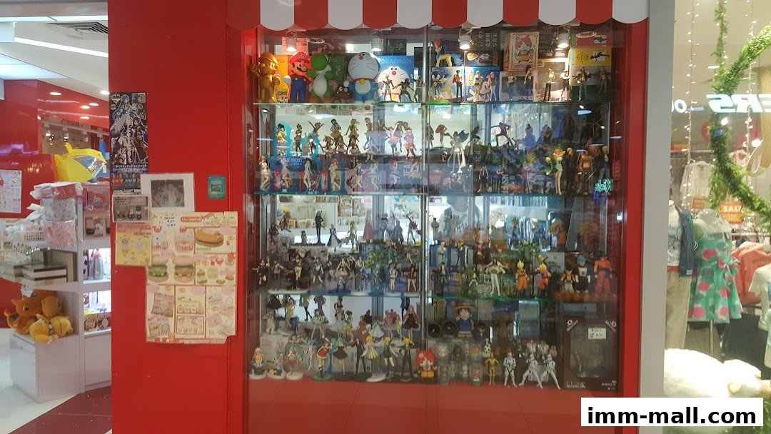A shop display case filled with anime figurines and collectibles, with plush toys and posters on the side.