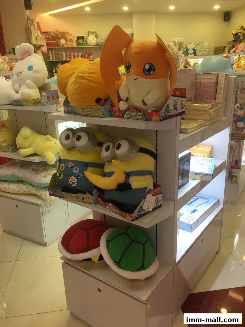 A retail display featuring plush toys including characters from Digimon and Minions.