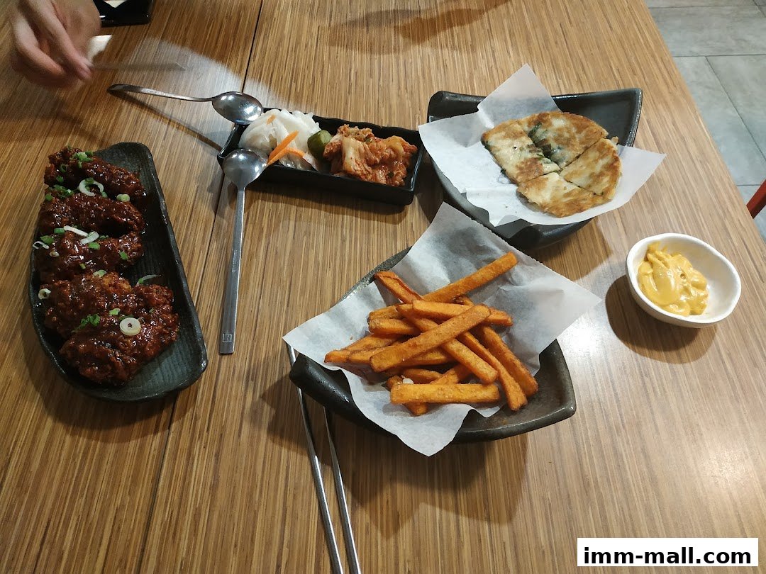 A table laden with Korean dishes including fried chicken, kimchi, fries, and a savory pancake.