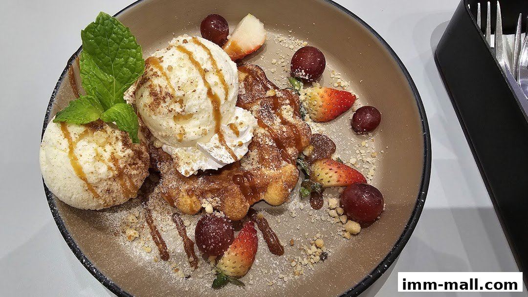 A delicious waffle dessert with ice cream, strawberries, grapes, and mint.