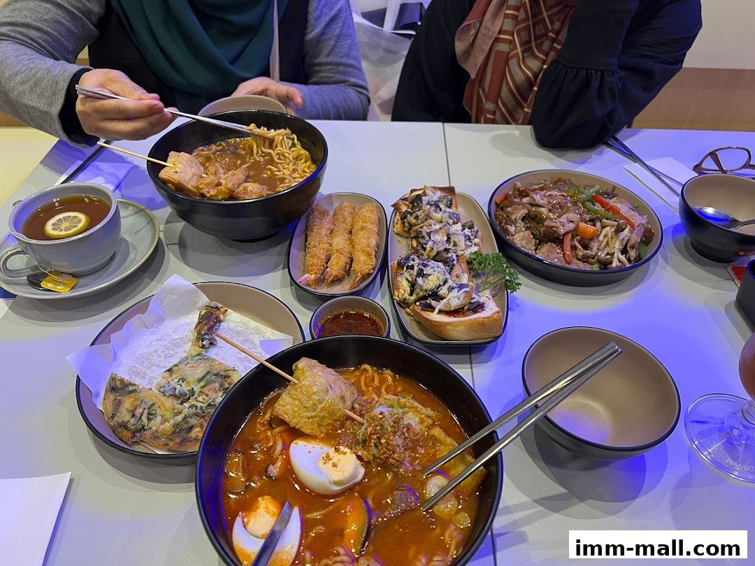A table laden with various Korean dishes, including hot pot, fried items, and drinks.
