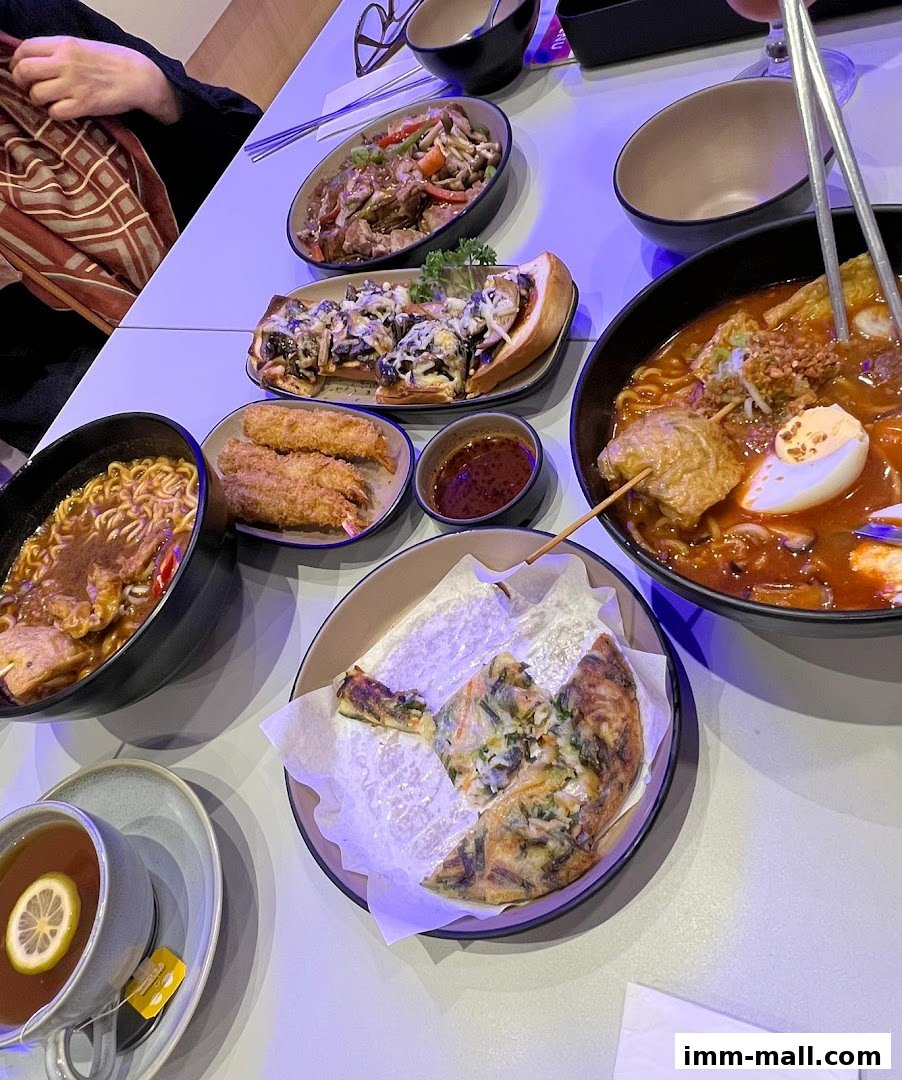 A table laden with various Korean dishes, including hotpot, noodles, and fried items.