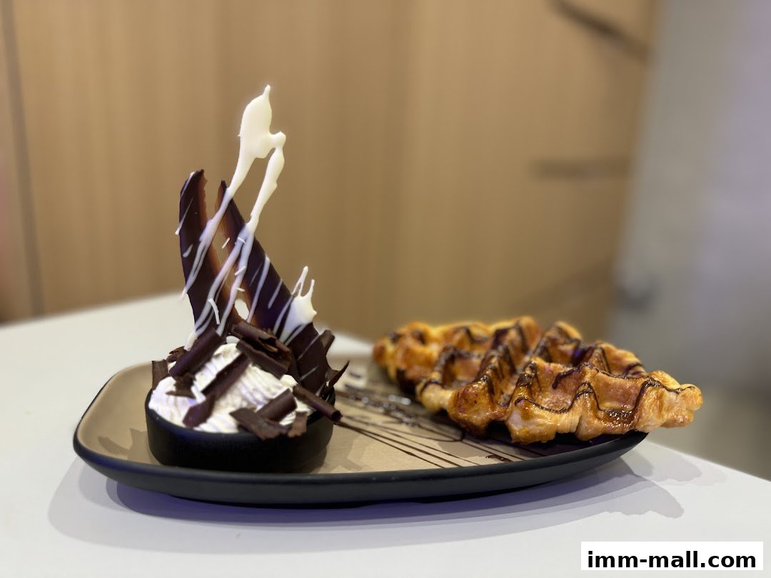 A plate with a chocolate tart and waffles drizzled with chocolate sauce.