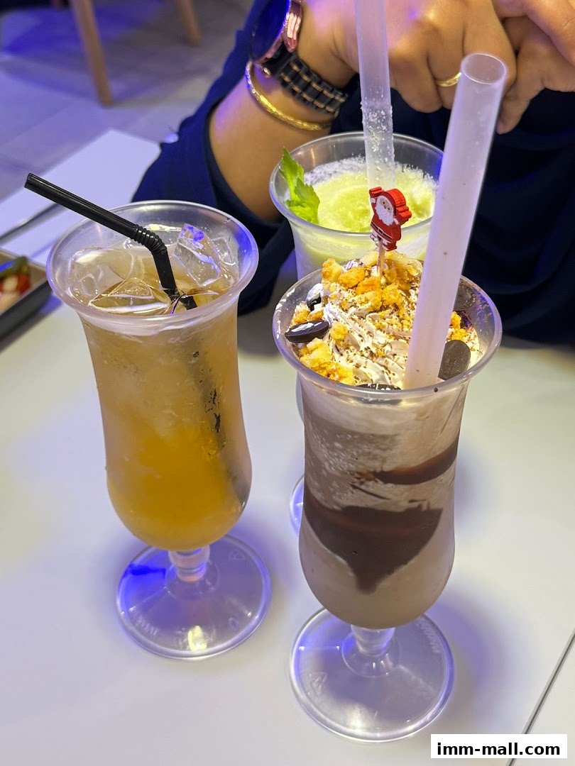 Three refreshing drinks, including a chocolate milkshake and two fruit beverages, are displayed on a white table.