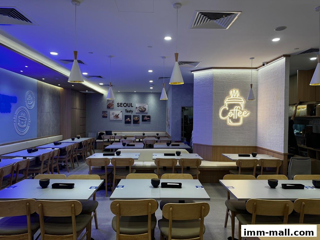 Interior of a modern restaurant with tables set for dining and a neon 'Coffee' sign.