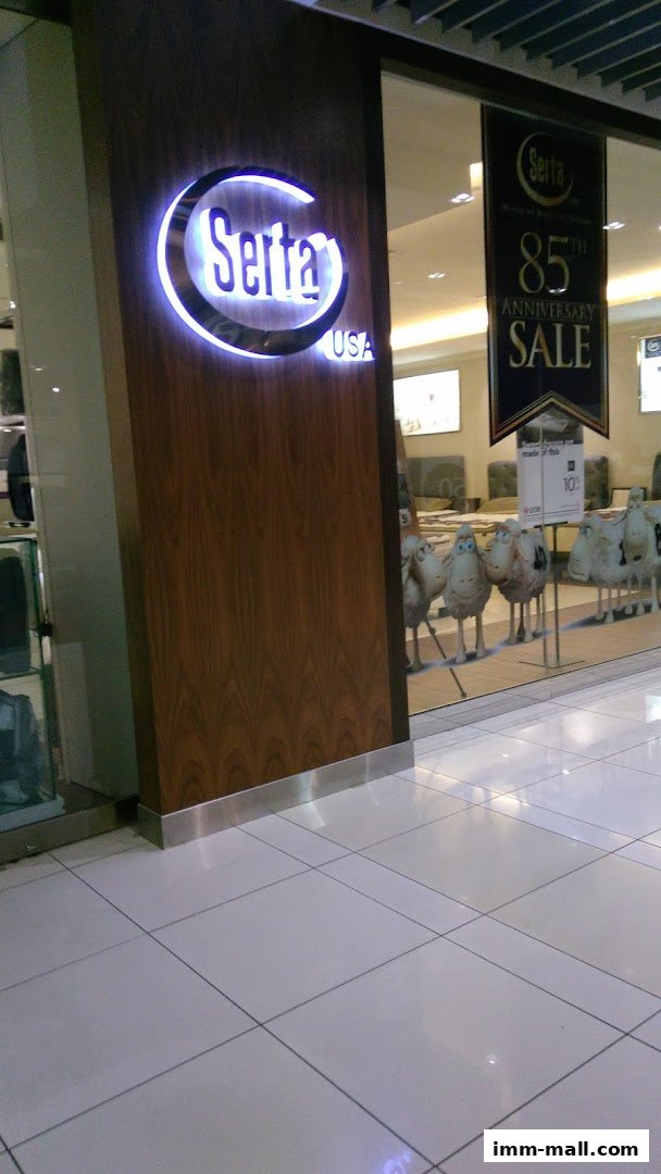 Serta Sleep Center IMM shop front with illuminated logo and anniversary sale banner.