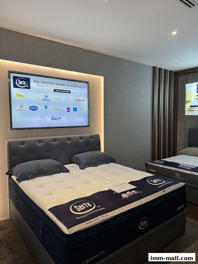 A Serta mattress display featuring a large screen showcasing hospitality brands and a comfortable bed.
