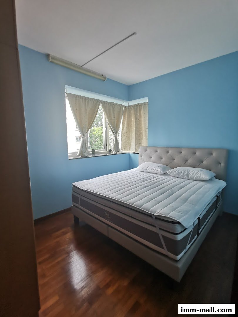 A Serta mattress on a bed frame in a room with blue walls and a window.