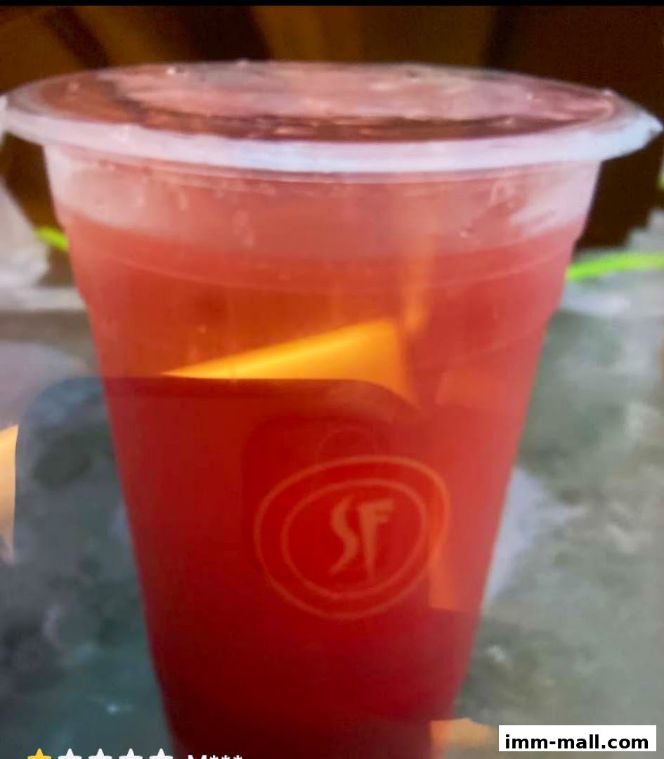 A close-up of a red fruit juice in a clear plastic cup with the SF logo.
