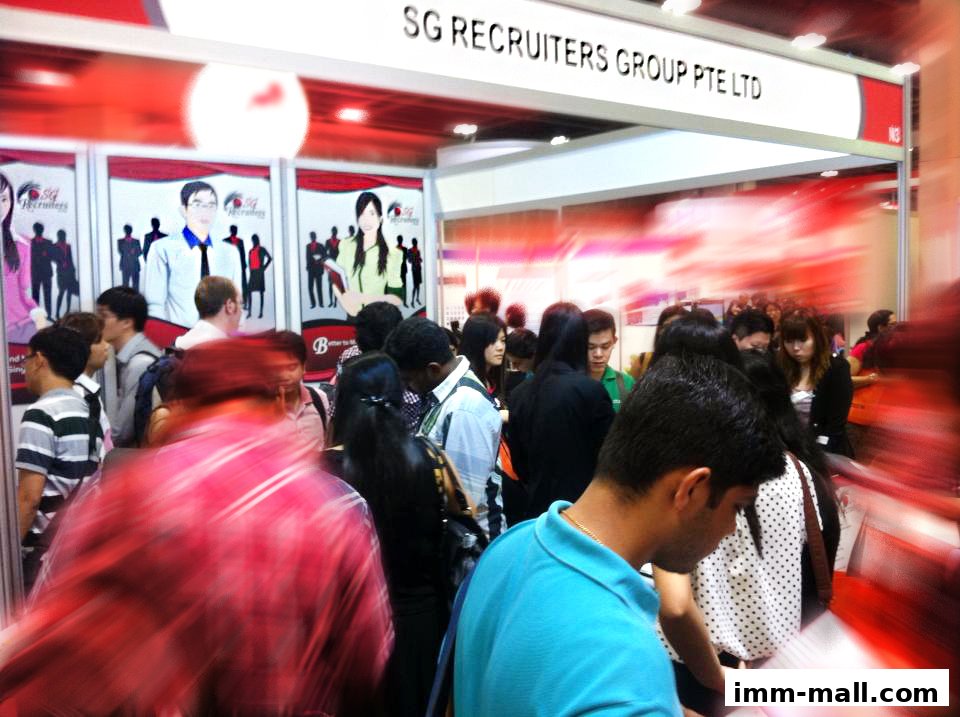 A busy recruitment event with people gathered around a booth for SG Recruiters Group Pte Ltd.