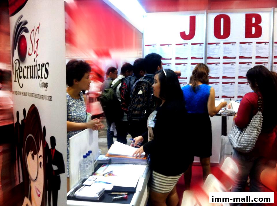 People at a job fair booth with 'JOB' signage and recruitment materials.