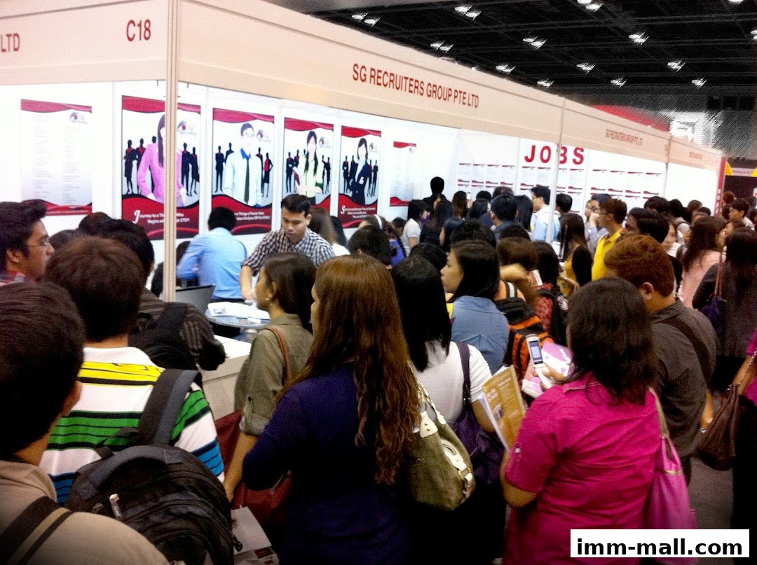 A busy recruitment fair with many people queuing at the SG Recruiters Group Pte Ltd booth.