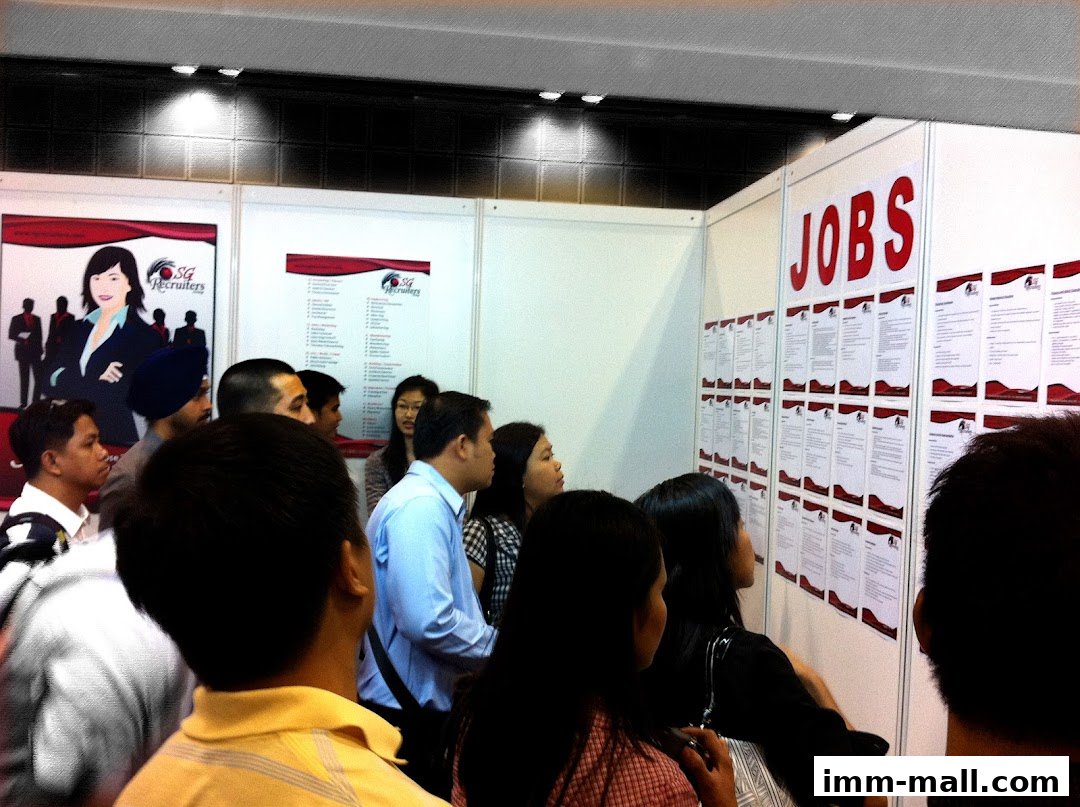 People gathered around a wall displaying job listings at SG Recruiters Group.