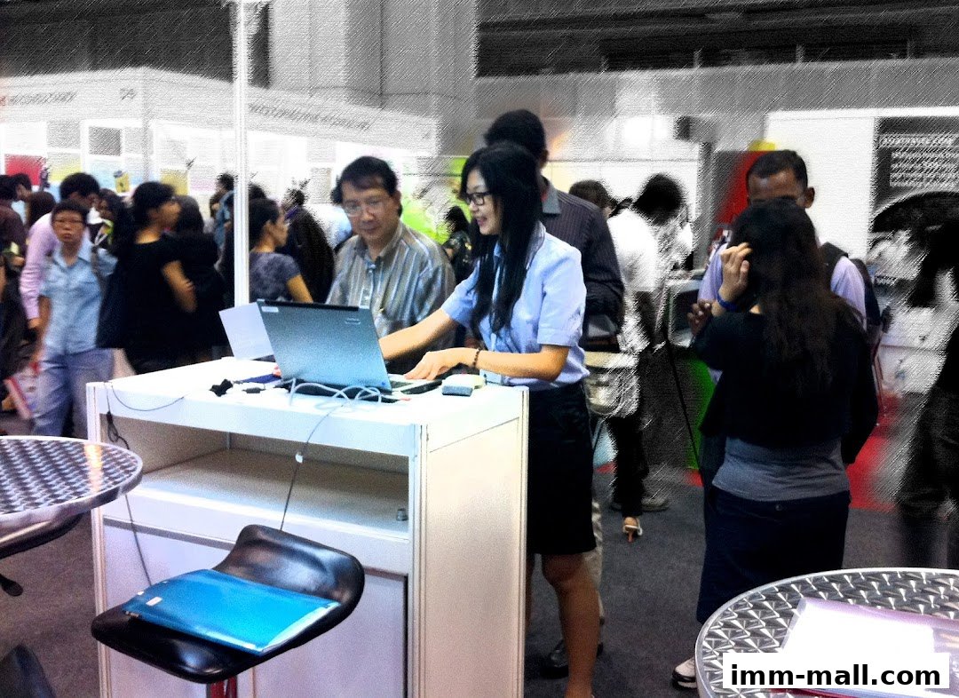 People gathered around a display table with a laptop at what appears to be a recruitment or career fair.